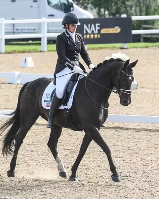 Amanda riding Hermione P, a black mare, at an outdoor international