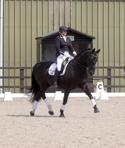 Amanda riding Remi II, a dark bay gelding, in an outdoor arena