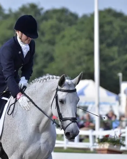 Amanda riding Run of the Mill, a grey mare, at an outdoor show