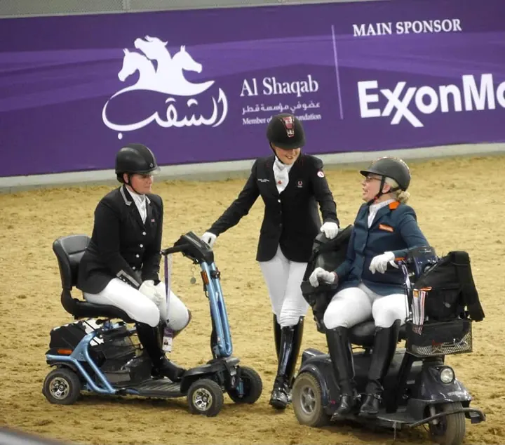 Amanda and two other para riders on mobility scooters chatting in the arena at CHI Al Shaqab, Doha