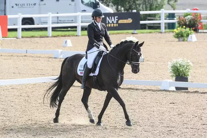 Amanda riding the black mare Hermione P in an outdoor arena