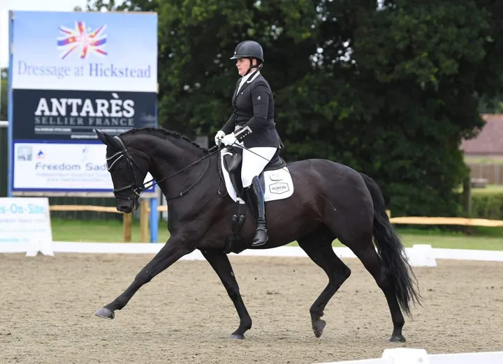 Amanda riding a black horse in trot at Dressage at Hickstead
