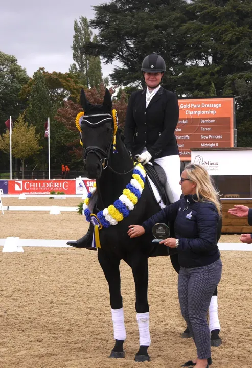 Amanda’s black horse New Princess wearing a championship garland at a prize-giving