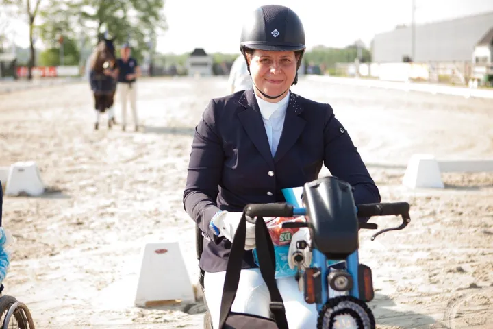 Amanda in competition jacket and breeches on her mobility scooter at a show