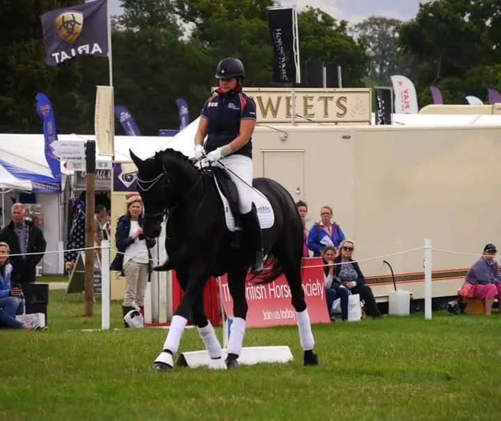 Amanda riding a black horse in a ridden demonstration at a showground