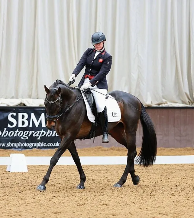 Amanda in Great Britain team jacket riding Kirkstall Spirit in an indoor arena