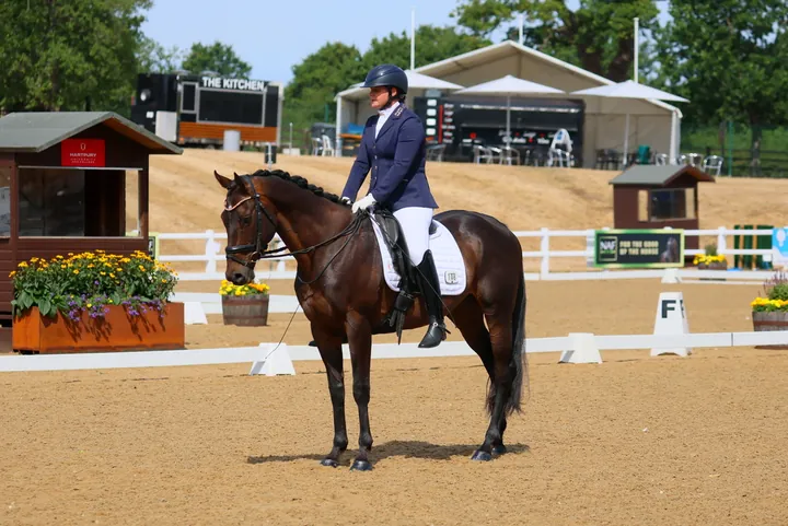 Amanda in a navy show jacket on her bay gelding Kirkstall Spirit, standing at halt in the outdoor arena at Hartpury