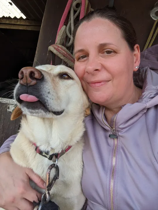 Amanda hugging a pale Labrador-type dog
